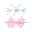 Two mini grosgrain bows, one white with blue stitching and one light pink, placed on white background.
