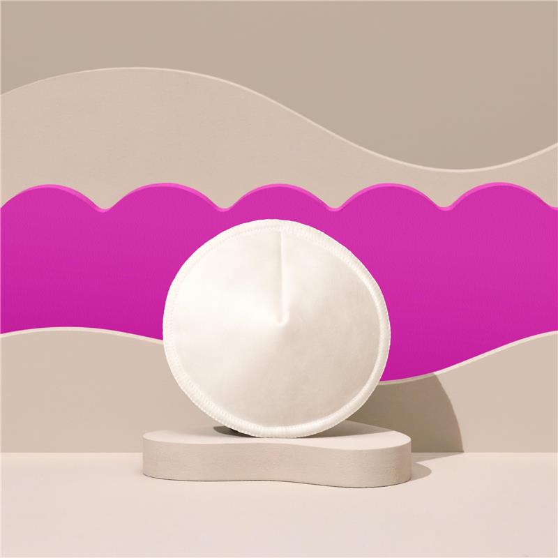 Reusable nursing pad displayed against a colorful abstract background, emphasizing its soft, round, white design.