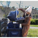 A woman attaches a Nuna infant car seat to a Wonderfold W4 Series stroller adapter in an outdoor setting.