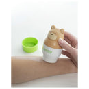 Yaya Organics Sun-Easy Teddy Bear pink sunscreen applicator being used on an arm, with a green cap nearby.