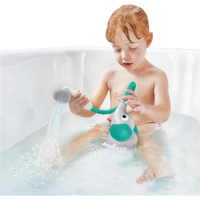 A toddler plays with a green Yookidoo elephant bath shower head, using its trunk spout rinser in a tub filled with water.