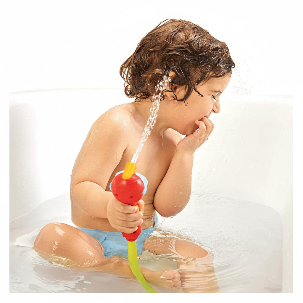 Child with short hair in the bath, joyfully spraying water from a red and blue whale-shaped toy.
