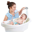 Woman joyfully bathes a baby in a white tub using a pink Yookidoo Elephant shower toy.