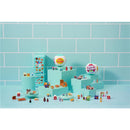 Colorful mini food items and packaging displayed with the Zoofy Zuru Mini Brands Fill The Fridge Playset, featuring a small fridge.