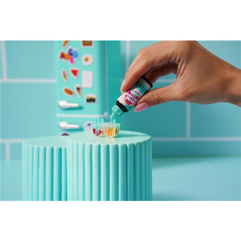 A hand pours colorful liquid from a bottle into small cups on a mint green countertop, featuring the Zoofy Zuru Mini Brands Fill The Fridge Playset.
