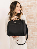 JuJuBe Insulated Bottle Bag in black held by a woman, featuring a zippered compartment and branding on the front.